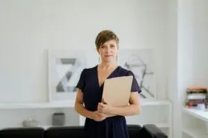 Confident woman with short hair in office setting holding a clipboard, symbolizing professionalism.